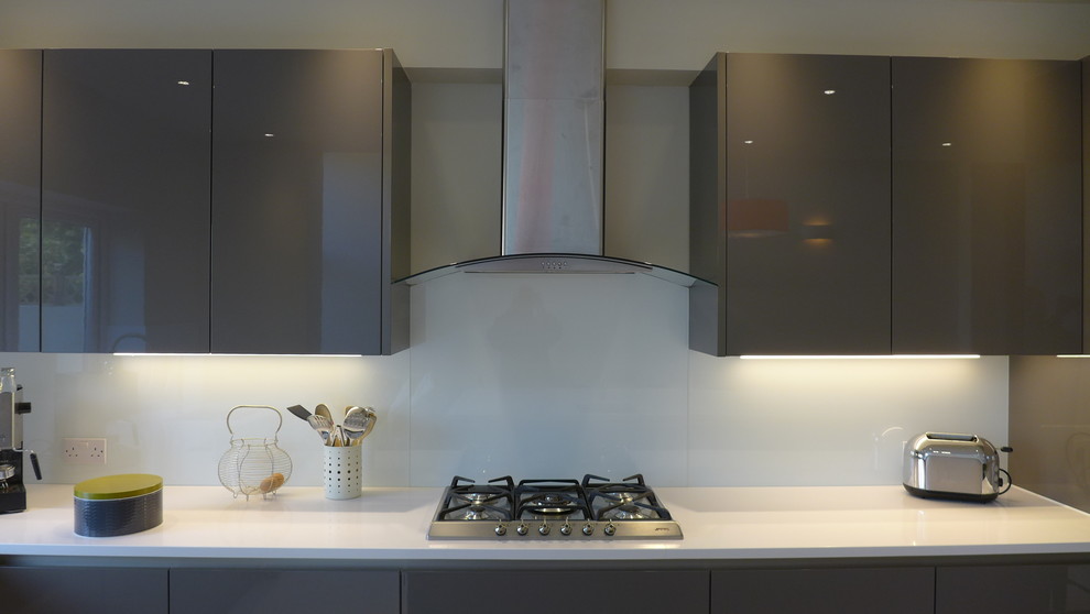 This is an example of a medium sized contemporary l-shaped open plan kitchen in Other with a submerged sink, flat-panel cabinets, grey cabinets, quartz worktops, white splashback, glass sheet splashback, stainless steel appliances, porcelain flooring and an island.
