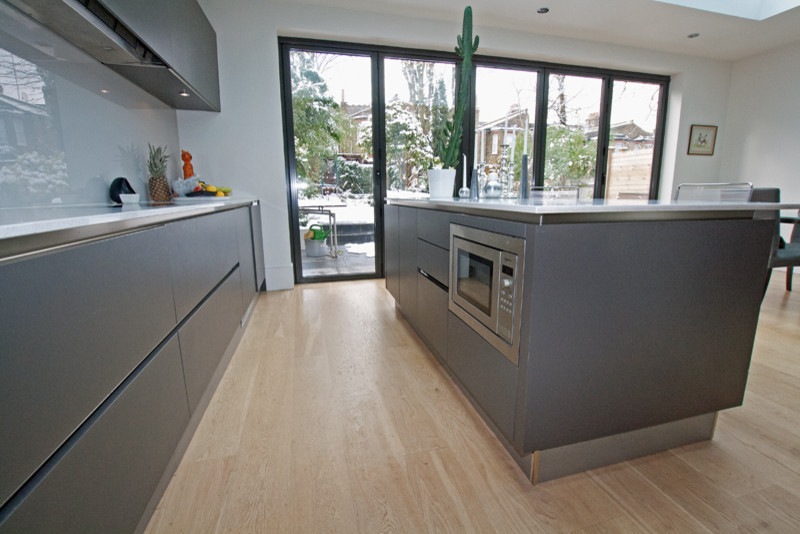 Moderne Küche mit grauen Schränken, Kücheninsel und Küchengeräten aus Edelstahl in London