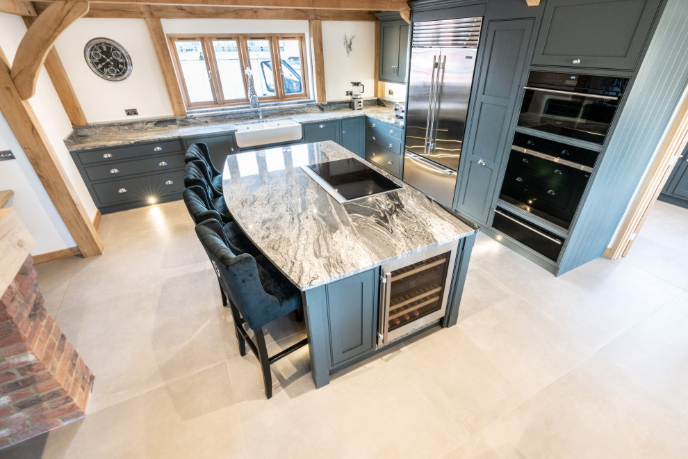 Inspiration for an expansive traditional l-shaped open plan kitchen in Essex with a double-bowl sink, recessed-panel cabinets, grey cabinets, granite worktops, integrated appliances, travertine flooring, an island, beige floors and grey worktops.