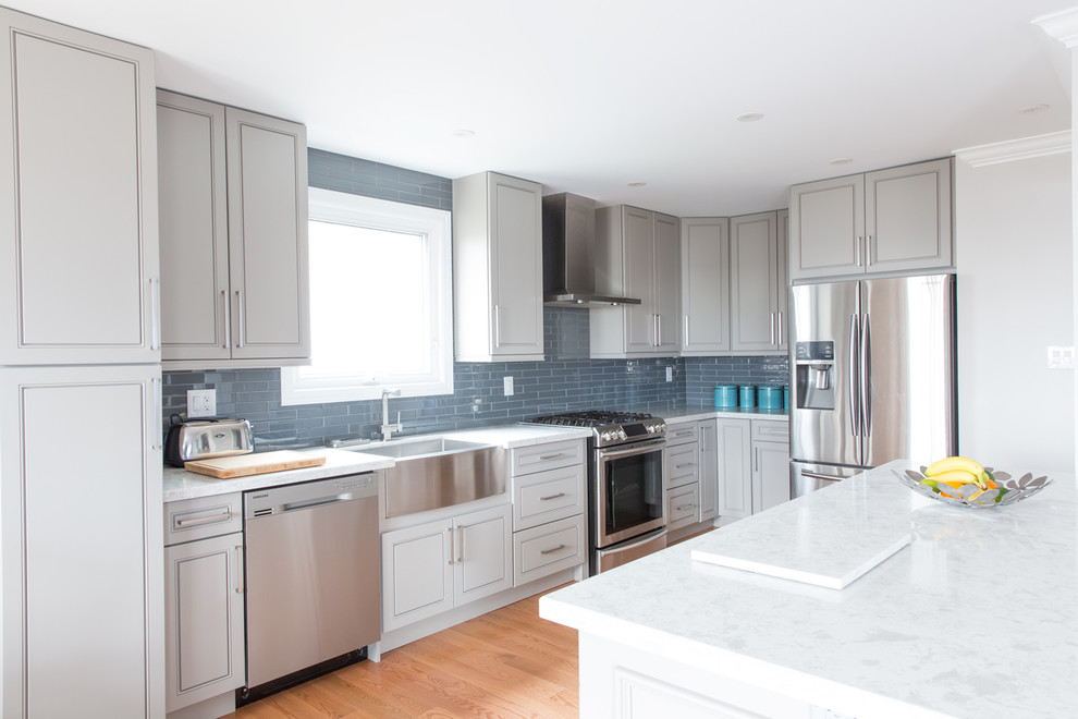 Example of a mid-sized transitional l-shaped medium tone wood floor and brown floor eat-in kitchen design in Toronto with a farmhouse sink, flat-panel cabinets, gray cabinets, quartz countertops, black backsplash, ceramic backsplash, stainless steel appliances and a peninsula