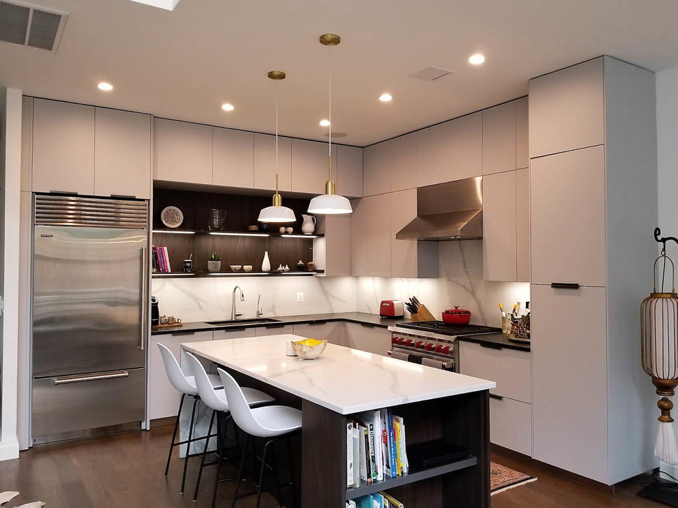 Design ideas for a medium sized modern l-shaped open plan kitchen in New York with a submerged sink, flat-panel cabinets, grey cabinets, engineered stone countertops, white splashback, stone slab splashback, stainless steel appliances, dark hardwood flooring, an island, brown floors and multicoloured worktops.