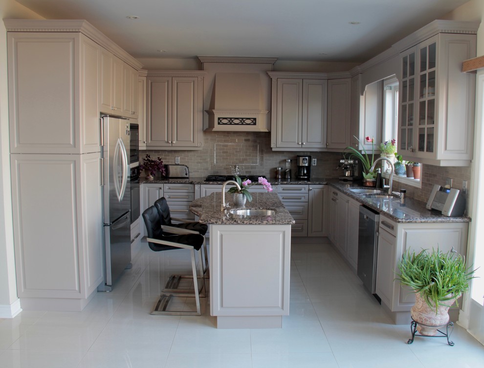 Klassisk inredning av ett stort kök, med en undermonterad diskho, luckor med upphöjd panel, grå skåp, granitbänkskiva, grått stänkskydd, stänkskydd i stenkakel, rostfria vitvaror, klinkergolv i porslin och en köksö