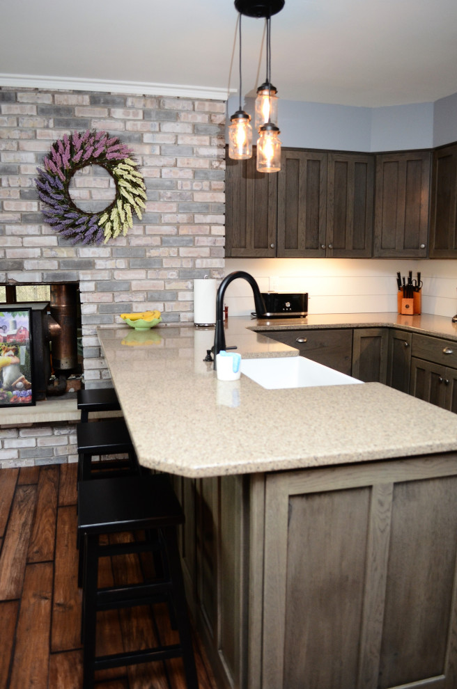 Exempel på ett mellanstort rustikt brun brunt kök, med en rustik diskho, luckor med infälld panel, grå skåp, bänkskiva i kvartsit, vitt stänkskydd, vita vitvaror, laminatgolv, en halv köksö och brunt golv