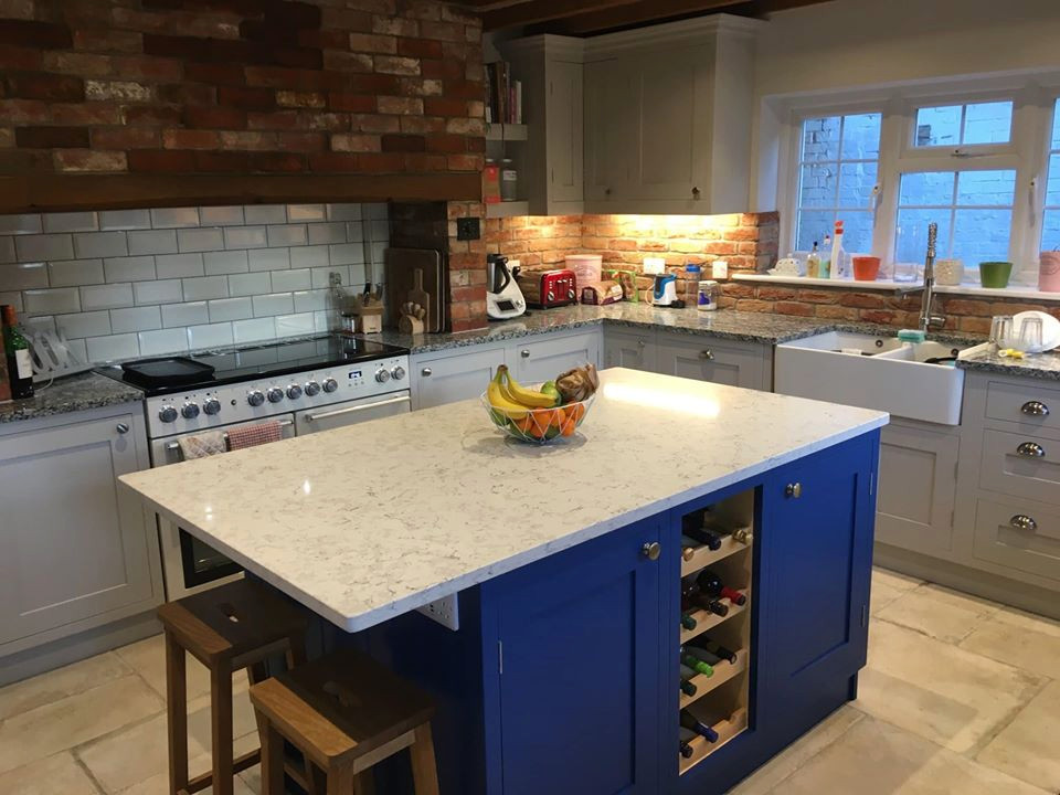 Modelo de cocinas en L moderna con fregadero sobremueble, puertas de armario azules, encimera de cuarcita, electrodomésticos de colores, una isla y encimeras blancas