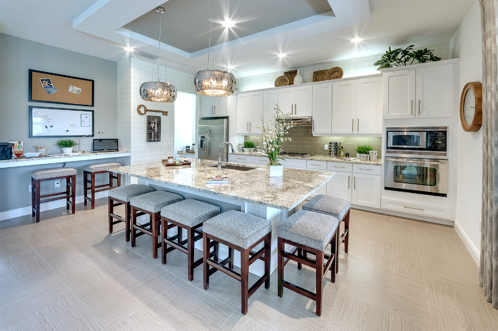 Large contemporary galley open plan kitchen in Tampa with a built-in sink, shaker cabinets, white cabinets, granite worktops, green splashback, glass tiled splashback, stainless steel appliances and an island.