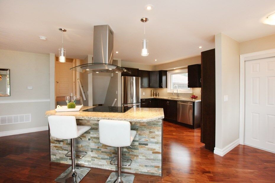 Photo of a contemporary kitchen in Toronto with stainless steel appliances, dark hardwood flooring and an island.