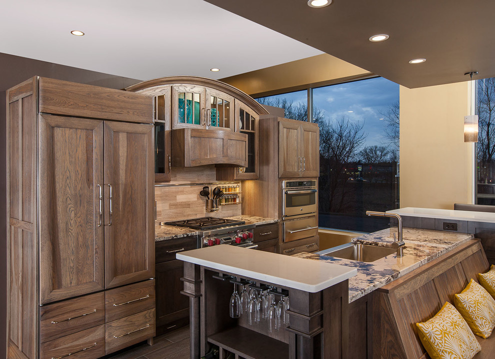 This is an example of a large classic galley kitchen/diner in Minneapolis with a belfast sink, recessed-panel cabinets, medium wood cabinets, granite worktops, beige splashback, porcelain splashback, stainless steel appliances, porcelain flooring and an island.