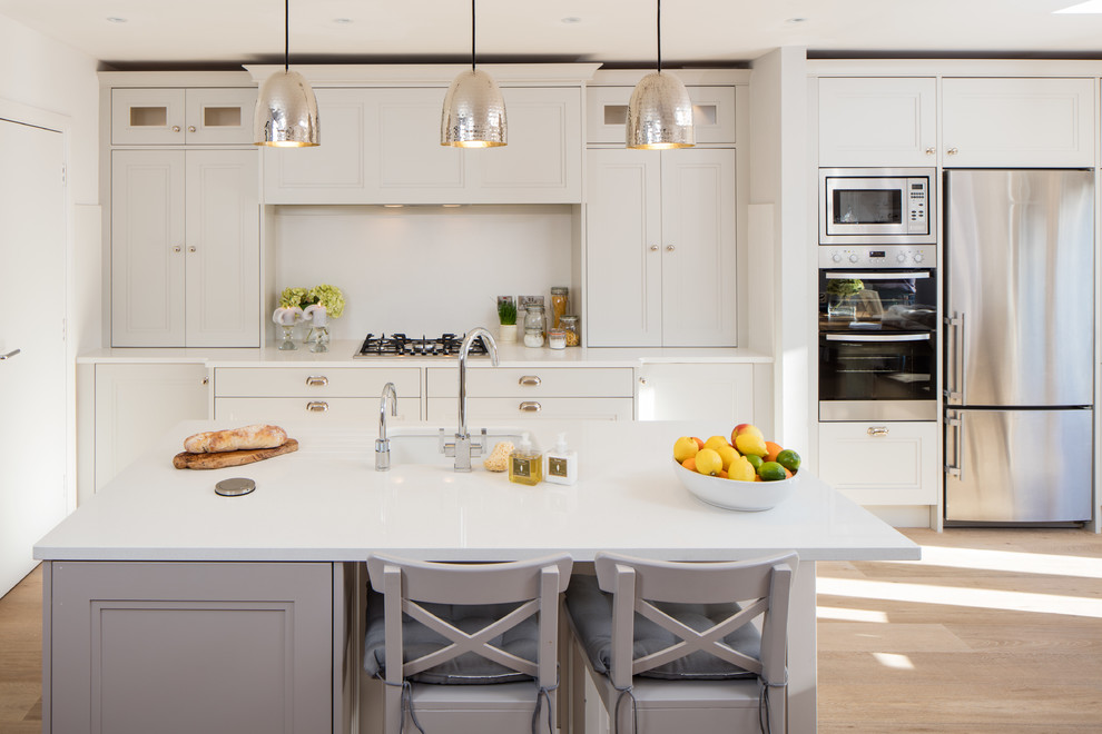 Foto di una cucina classica con ante a filo, elettrodomestici in acciaio inossidabile, parquet chiaro e pavimento beige