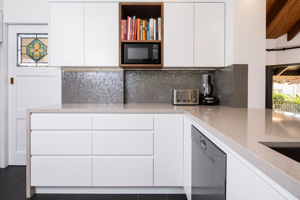 Mid-sized danish l-shaped porcelain tile and gray floor enclosed kitchen photo in Brisbane with an undermount sink, flat-panel cabinets, white cabinets, quartz countertops, metallic backsplash, mosaic tile backsplash, stainless steel appliances and gray countertops