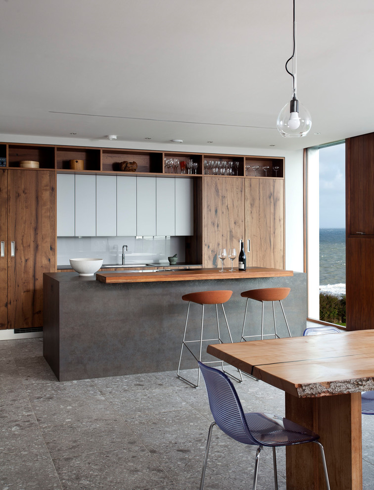 Inspiration for a medium sized contemporary single-wall open plan kitchen in Belfast with a belfast sink, flat-panel cabinets, dark wood cabinets, integrated appliances and an island.
