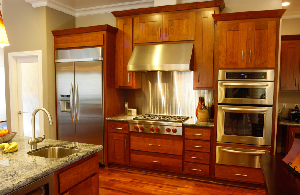 This is an example of a large contemporary u-shaped kitchen/diner in San Francisco with a submerged sink, shaker cabinets, medium wood cabinets, granite worktops, metallic splashback, stainless steel appliances, medium hardwood flooring, an island and brown floors.