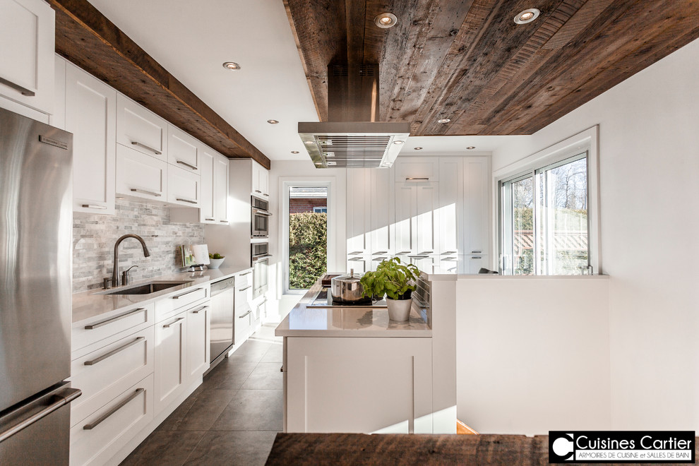 Example of a large trendy concrete floor open concept kitchen design in Montreal with a double-bowl sink, shaker cabinets, white cabinets, quartzite countertops, white backsplash, stone tile backsplash, stainless steel appliances and an island