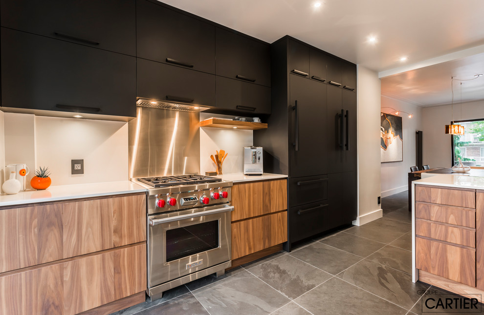 Inspiration for a mid-sized modern galley slate floor and black floor open concept kitchen remodel in Montreal with an undermount sink, flat-panel cabinets, black cabinets, solid surface countertops, gray backsplash, ceramic backsplash, stainless steel appliances and a peninsula
