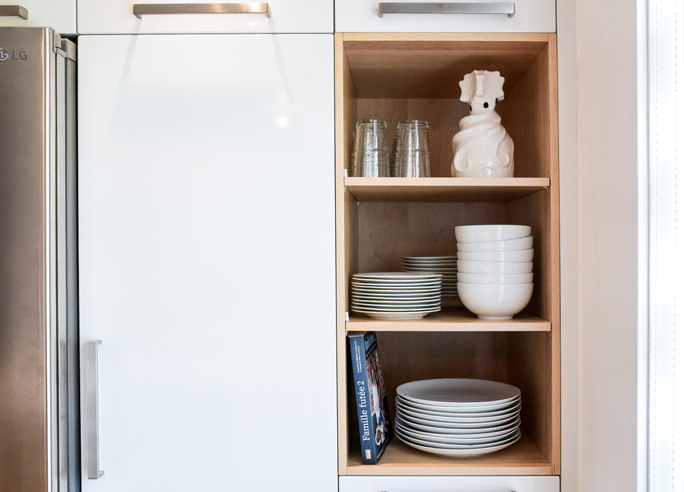 This is an example of a small scandi l-shaped enclosed kitchen in Montreal with a submerged sink, flat-panel cabinets, white cabinets, quartz worktops, white splashback, ceramic splashback, stainless steel appliances, medium hardwood flooring, an island and orange floors.
