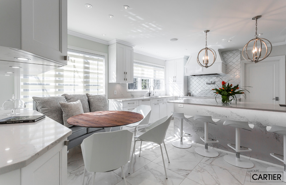 Inspiration for an expansive traditional l-shaped kitchen/diner in Montreal with a submerged sink, shaker cabinets, white cabinets, quartz worktops, grey splashback, glass tiled splashback, integrated appliances, marble flooring and an island.