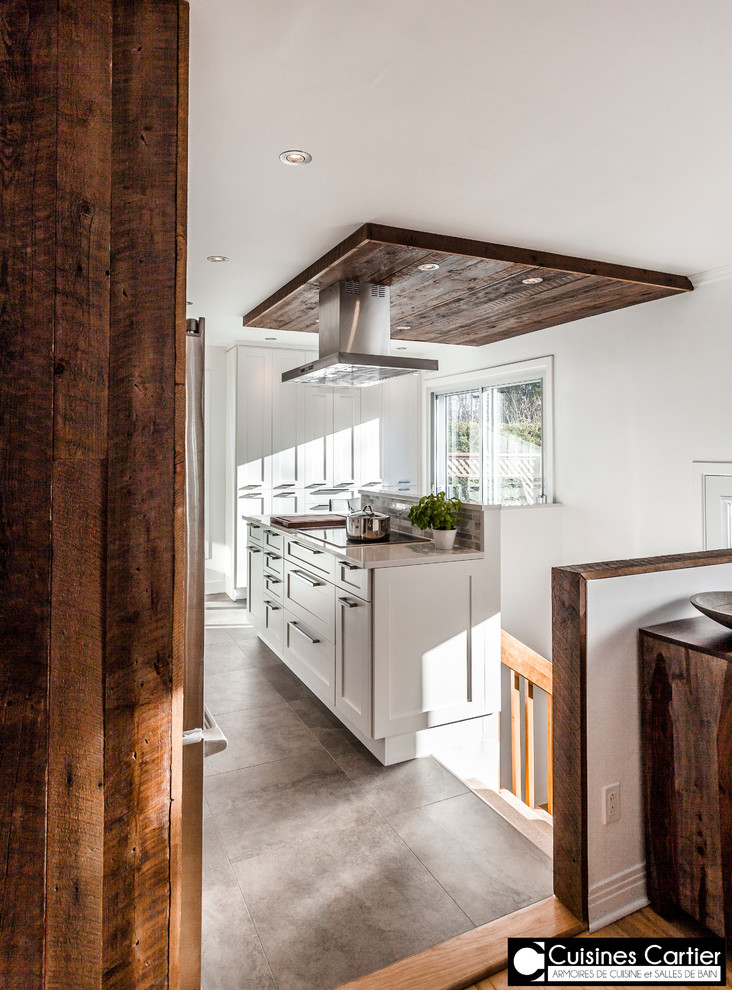 Bild på ett stort funkis kök med öppen planlösning, med en dubbel diskho, skåp i shakerstil, vita skåp, bänkskiva i kvartsit, vitt stänkskydd, stänkskydd i stenkakel, rostfria vitvaror, betonggolv och en köksö