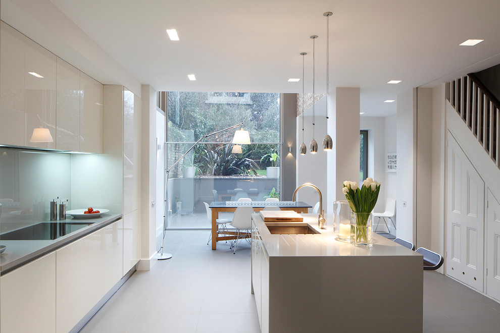 Zweizeilige Moderne Wohnküche mit Unterbauwaschbecken, flächenbündigen Schrankfronten, weißen Schränken, Küchenrückwand in Grau und Kücheninsel in London