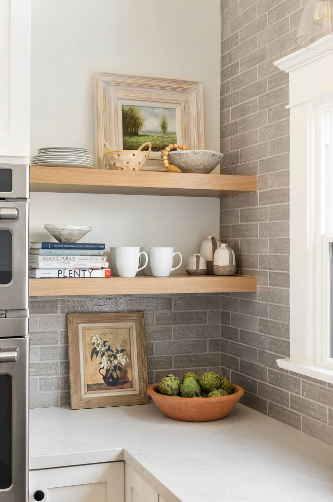 Foto på ett mellanstort amerikanskt vit kök, med en rustik diskho, skåp i shakerstil, vita skåp, bänkskiva i kvarts, grått stänkskydd, stänkskydd i keramik, rostfria vitvaror, klinkergolv i porslin, en köksö och grått golv