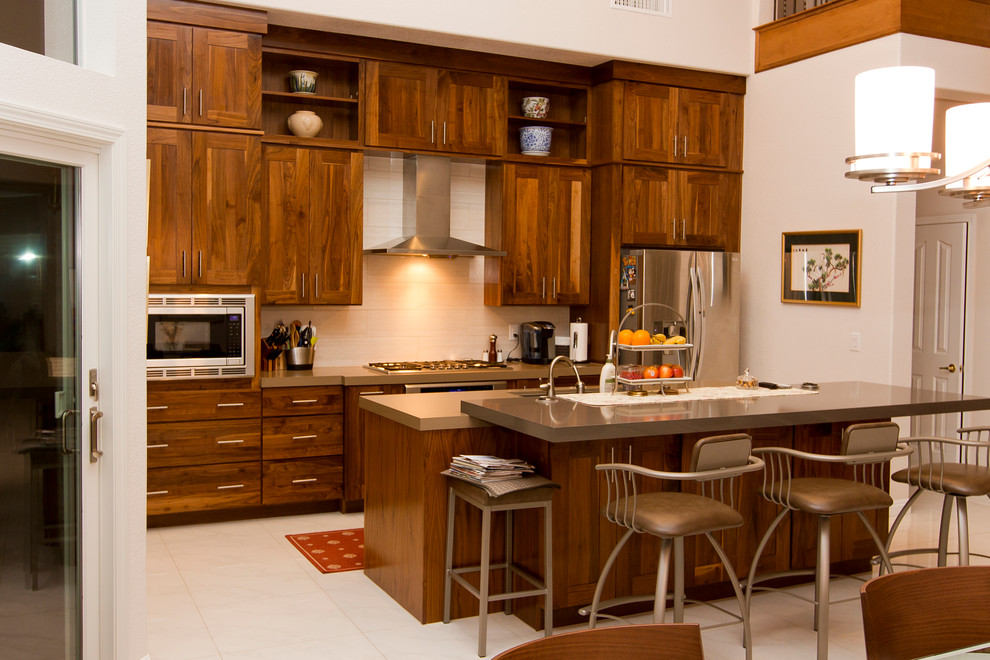 Modern inredning av ett stort linjärt kök med öppen planlösning, med en undermonterad diskho, skåp i shakerstil, skåp i mörkt trä, bänkskiva i kvarts, beige stänkskydd, stänkskydd i porslinskakel, rostfria vitvaror, klinkergolv i porslin och en köksö
