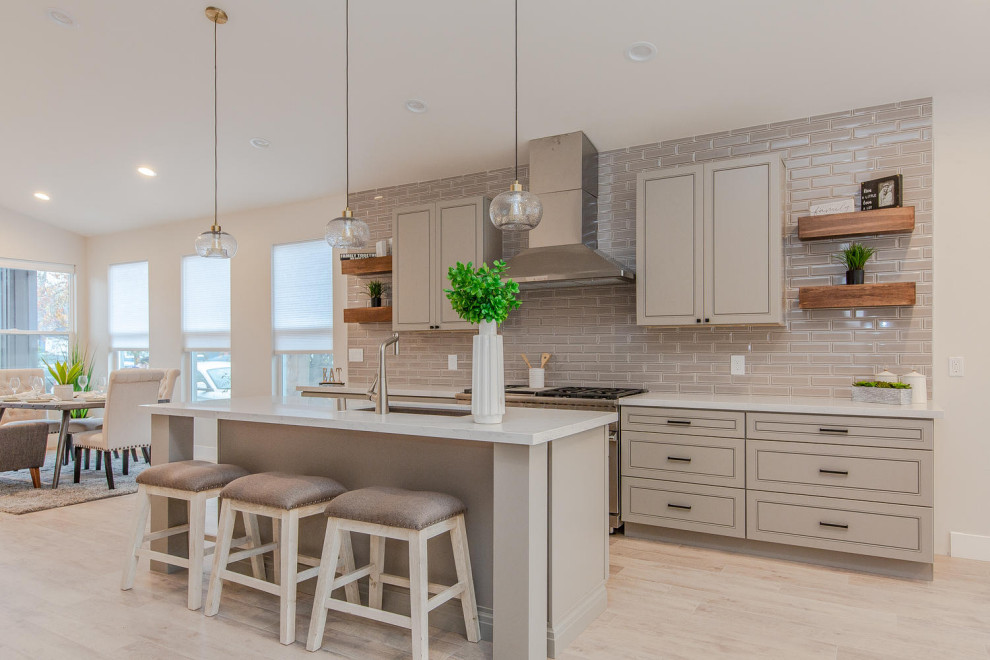 This is an example of a medium sized classic galley kitchen/diner in San Francisco with a submerged sink, raised-panel cabinets, grey cabinets, grey splashback, metro tiled splashback, stainless steel appliances, an island, beige floors and beige worktops.