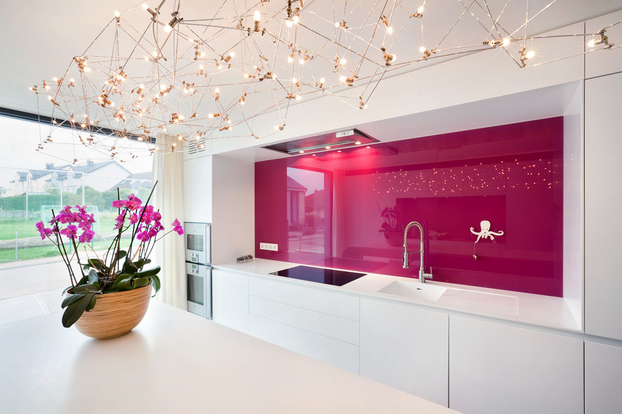 На фото: прямая кухня в стиле модернизм с обеденным столом, розовым фартуком и фартуком из стекла