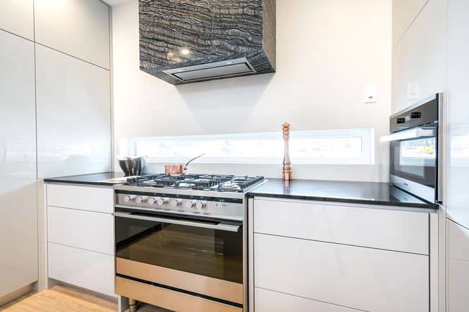 Esempio di una cucina minimal di medie dimensioni con ante lisce, ante grigie, top in granito, elettrodomestici in acciaio inossidabile e parquet chiaro