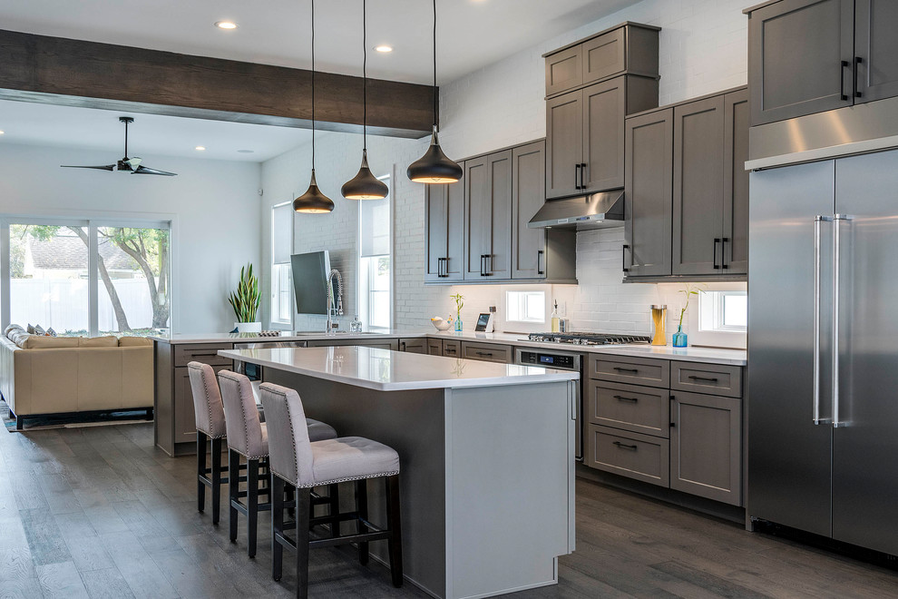 This is an example of a large traditional l-shaped open plan kitchen in Orlando with a submerged sink, shaker cabinets, marble worktops, white splashback, metro tiled splashback, stainless steel appliances, dark hardwood flooring, an island and grey cabinets.