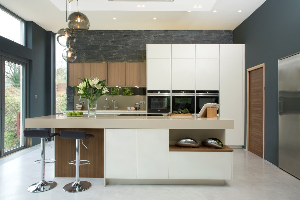 Modern inredning av ett beige beige kök, med släta luckor, vita skåp, svarta vitvaror, betonggolv, en köksö och grått golv