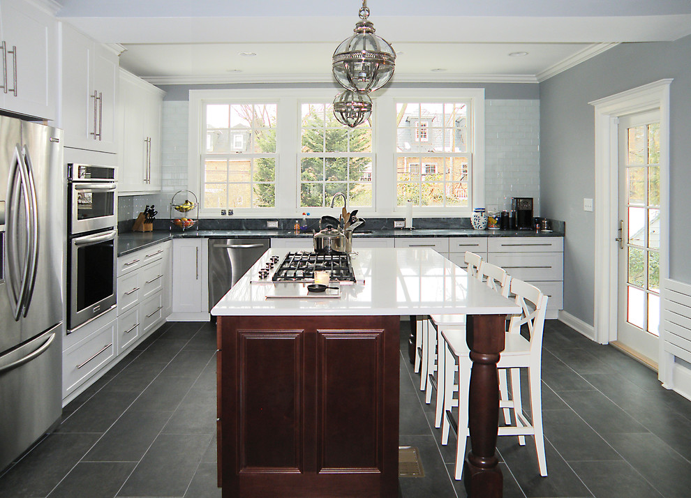 Exempel på ett avskilt, stort klassiskt l-kök, med en undermonterad diskho, luckor med upphöjd panel, skåp i mörkt trä, bänkskiva i täljsten, grönt stänkskydd, stänkskydd i glaskakel, rostfria vitvaror, klinkergolv i keramik och en köksö