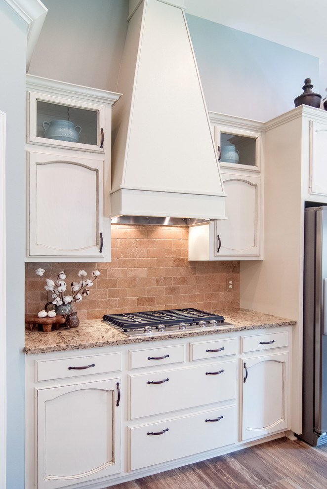 Example of a mid-sized transitional l-shaped medium tone wood floor kitchen design in New Orleans with quartz countertops, an island, an undermount sink, recessed-panel cabinets, white cabinets, beige backsplash, subway tile backsplash and stainless steel appliances