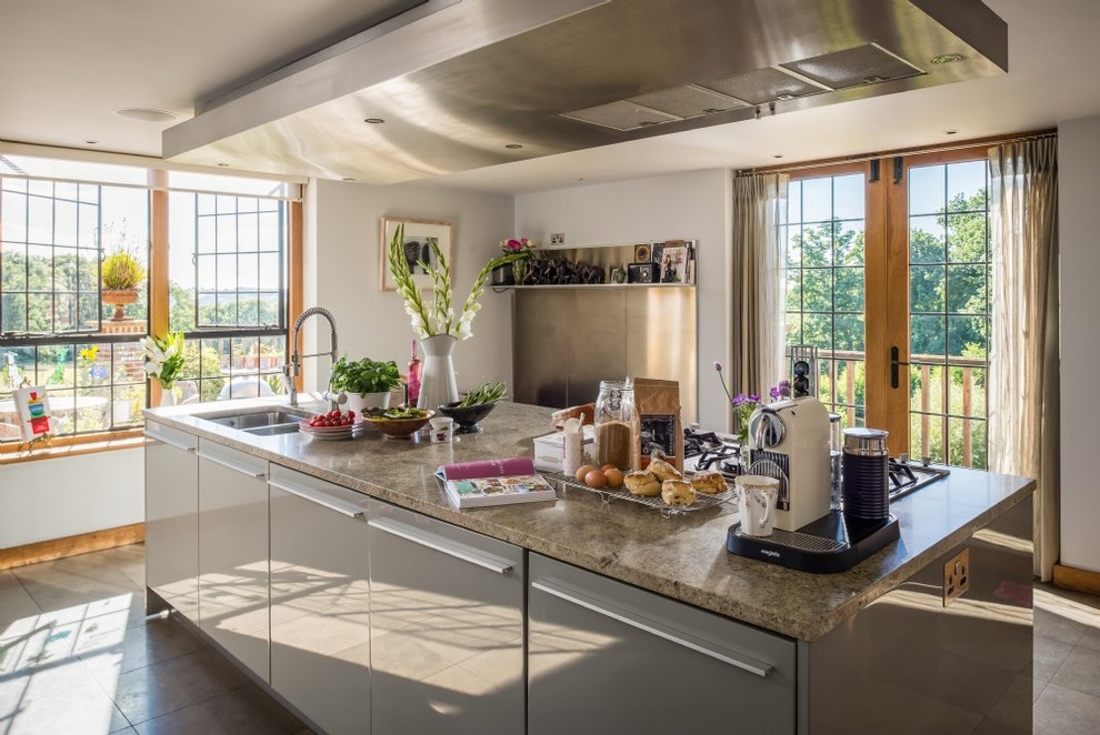 This is an example of a large urban open plan kitchen in Surrey with a double-bowl sink, flat-panel cabinets, grey cabinets, marble worktops, stainless steel appliances, terracotta flooring, an island, metallic splashback and grey floors.