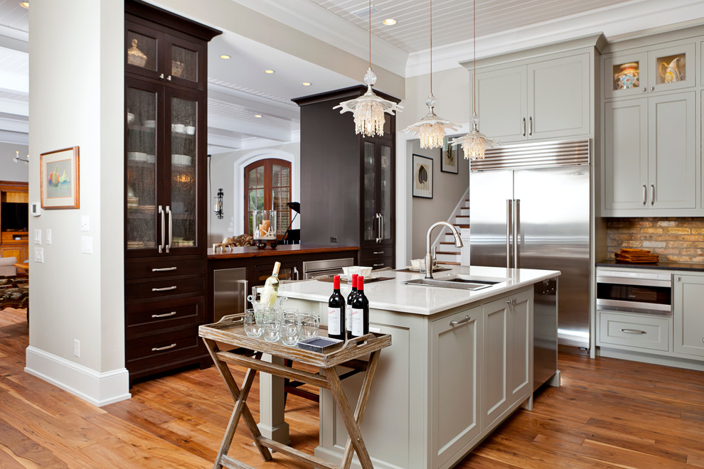 Modelo de cocina clásica con fregadero bajoencimera, armarios estilo shaker, puertas de armario grises y electrodomésticos de acero inoxidable