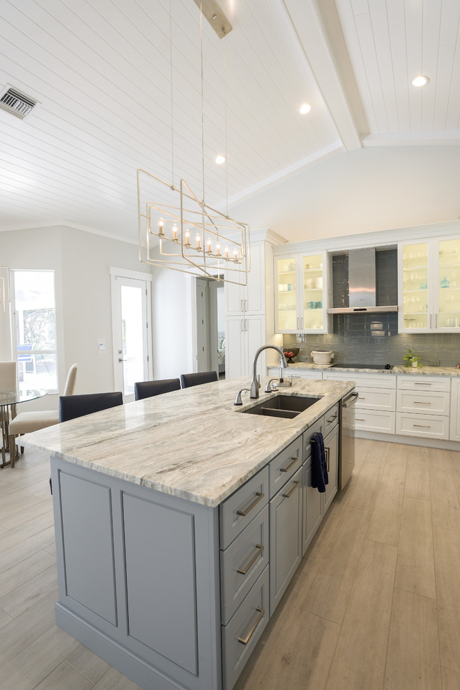 Modern inredning av ett mellanstort vit vitt kök, med en undermonterad diskho, skåp i shakerstil, vita skåp, bänkskiva i kvartsit, grått stänkskydd, stänkskydd i glaskakel, rostfria vitvaror, ljust trägolv, en köksö och beiget golv