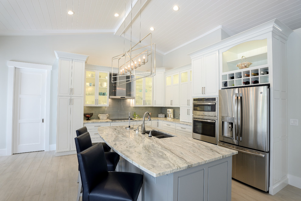 Example of a mid-sized trendy l-shaped light wood floor and beige floor open concept kitchen design in Other with an undermount sink, shaker cabinets, white cabinets, quartzite countertops, gray backsplash, glass tile backsplash, stainless steel appliances, an island and white countertops