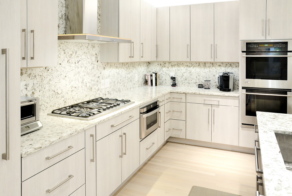 Diseño de cocina contemporánea con armarios con paneles lisos, puertas de armario grises, encimera de granito y electrodomésticos de acero inoxidable
