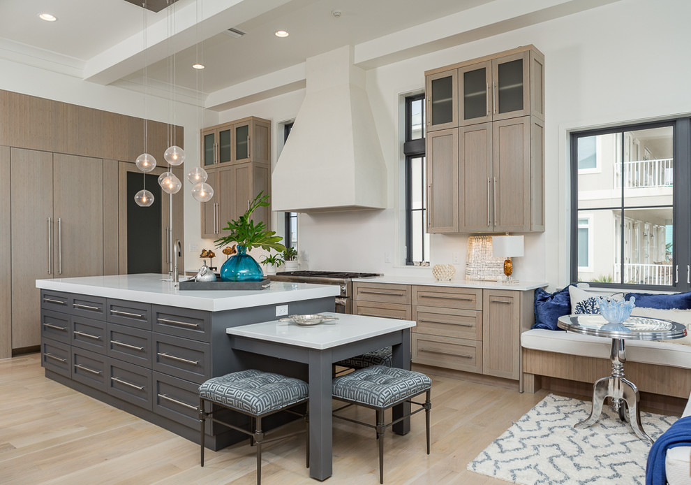 Medium sized beach style galley kitchen/diner in Miami with shaker cabinets, light wood cabinets, stainless steel appliances, light hardwood flooring, an island, a single-bowl sink and composite countertops.