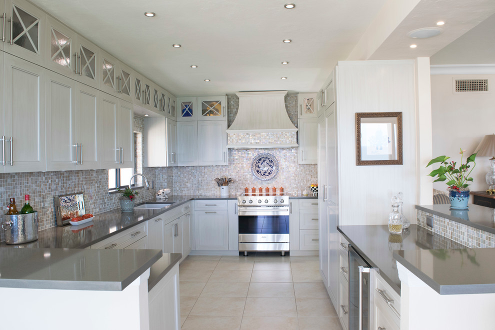 Photo of a medium sized traditional u-shaped kitchen/diner in Miami with a built-in sink, shaker cabinets, engineered stone countertops, beige splashback, mosaic tiled splashback, integrated appliances, white cabinets, ceramic flooring, no island and beige floors.
