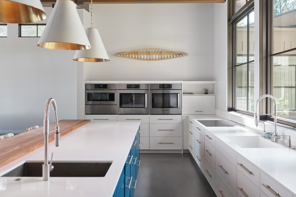 Inspiration for an expansive modern open plan kitchen in Grand Rapids with a belfast sink, white cabinets, stainless steel appliances, concrete flooring, an island, grey floors and white worktops.