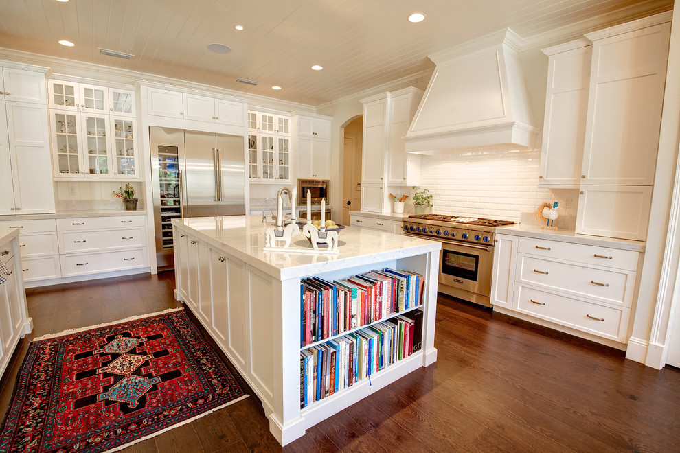 Inspiration for a traditional kitchen in Orlando with shaker cabinets, white cabinets, white splashback, metro tiled splashback, stainless steel appliances, medium hardwood flooring and an island.