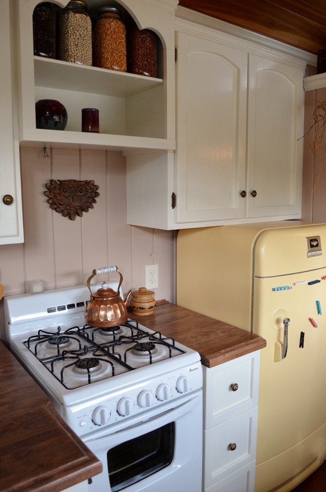 Bild på ett litet amerikanskt kök med öppen planlösning, med en undermonterad diskho, öppna hyllor, vita skåp, träbänkskiva, färgglada vitvaror och mellanmörkt trägolv
