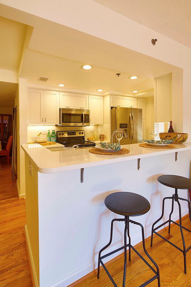 Inredning av ett modernt litet kök, med en undermonterad diskho, skåp i shakerstil, vita skåp, bänkskiva i kvarts, vitt stänkskydd, stänkskydd i tunnelbanekakel, rostfria vitvaror och en halv köksö