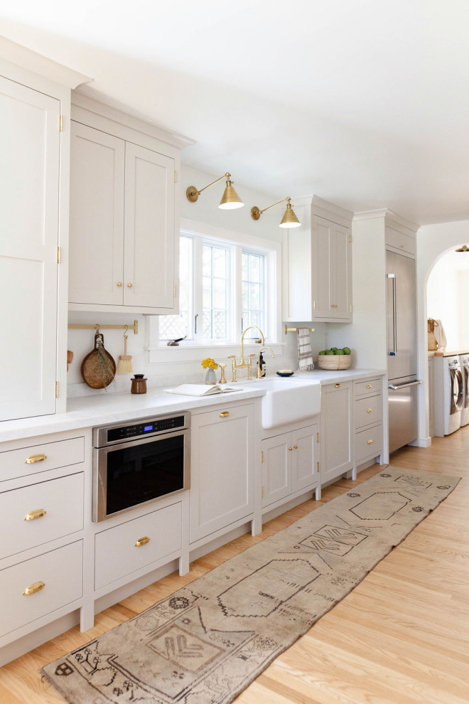 Transitional light wood floor and beige floor enclosed kitchen photo in Sacramento with a farmhouse sink, shaker cabinets, gray cabinets, stainless steel appliances and white countertops