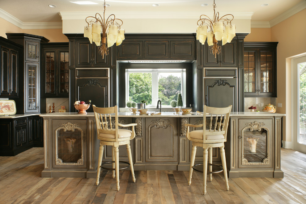 Exemple d'une cuisine encastrable victorienne en L avec un placard avec porte à panneau surélevé, des portes de placard noires, un sol en bois brun, îlot, un sol marron et un plan de travail gris.
