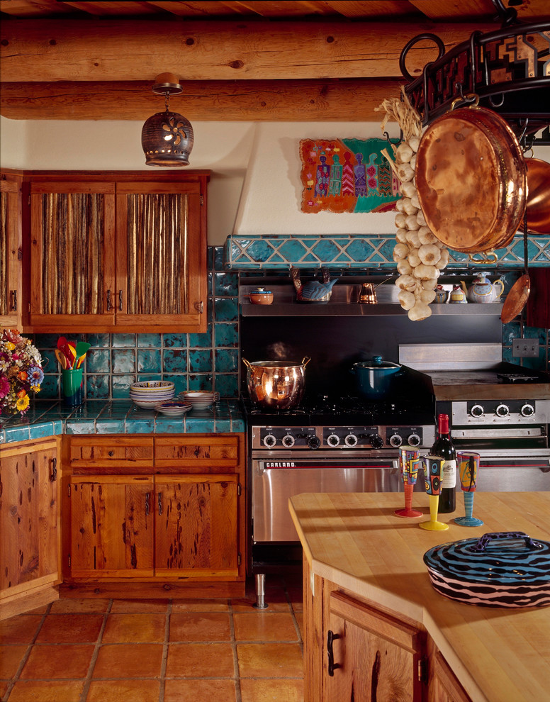Mediterrane Küche mit flächenbündigen Schrankfronten, Schränken im Used-Look, Küchenrückwand in Blau, Küchengeräten aus Edelstahl und braunem Boden in Phoenix