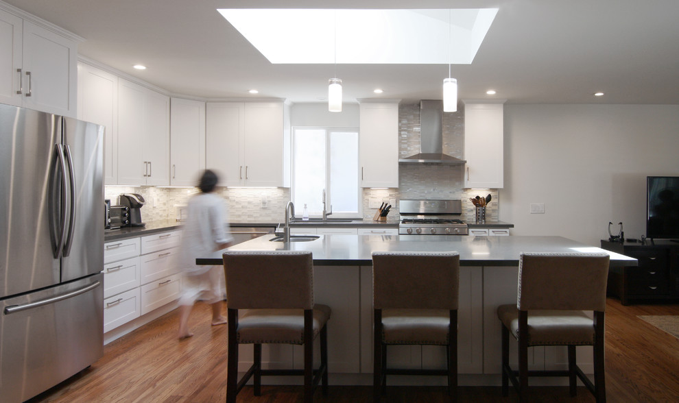 Exempel på ett mellanstort modernt grå grått kök, med en undermonterad diskho, skåp i shakerstil, vita skåp, bänkskiva i kvartsit, beige stänkskydd, stänkskydd i glaskakel, rostfria vitvaror, mellanmörkt trägolv, en köksö och brunt golv