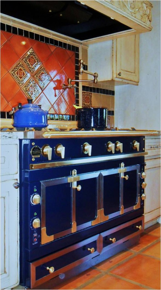 Foto di una cucina tradizionale di medie dimensioni con ante con riquadro incassato, ante beige, top in granito, paraspruzzi arancione, paraspruzzi con piastrelle in ceramica, elettrodomestici colorati e pavimento in terracotta