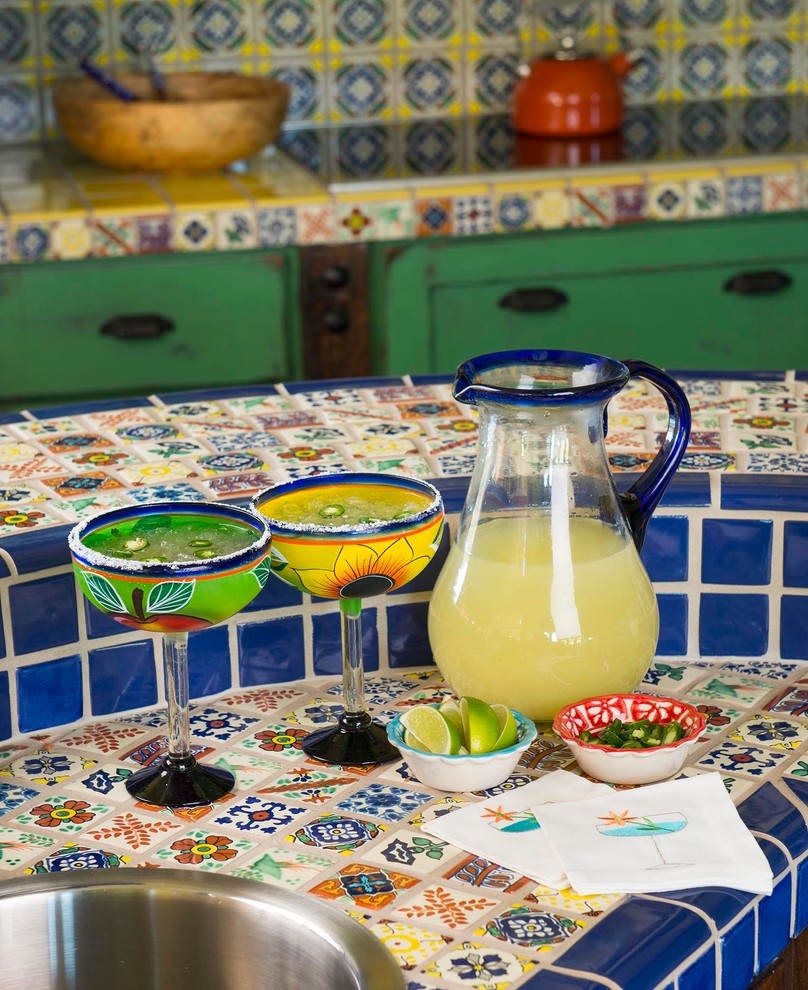 Exemple d'une cuisine sud-ouest américain avec un évier posé, plan de travail carrelé, une crédence bleue, une crédence en céramique, un électroménager en acier inoxydable et îlot.