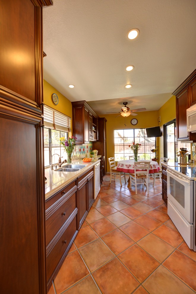 Photo of a mediterranean galley enclosed kitchen in San Diego with recessed-panel cabinets, medium wood cabinets, engineered stone countertops, green splashback, ceramic splashback, terracotta flooring, pink floors and beige worktops.