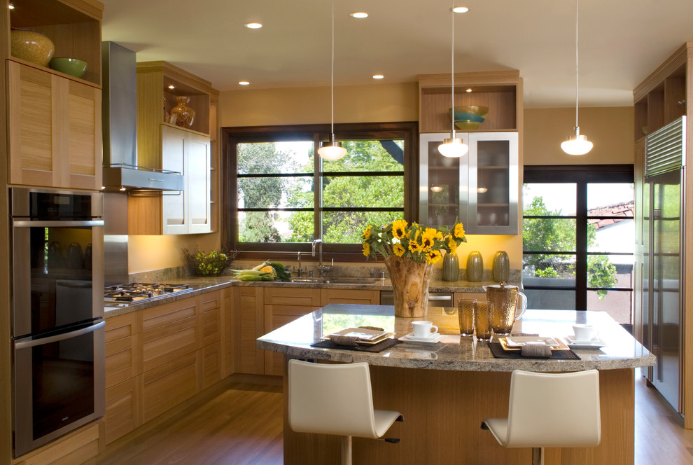 Bild på ett stort funkis kök, med en dubbel diskho, skåp i shakerstil, skåp i ljust trä, granitbänkskiva, brunt stänkskydd, stänkskydd i sten, rostfria vitvaror, mellanmörkt trägolv och en köksö