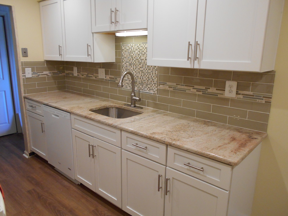 Example of a small classic galley light wood floor kitchen pantry design in Philadelphia with an undermount sink, recessed-panel cabinets, white cabinets, granite countertops, brown backsplash, glass tile backsplash and white appliances